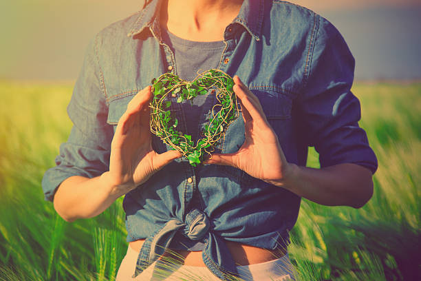 photo of female hands holding heart shaped toy in the field