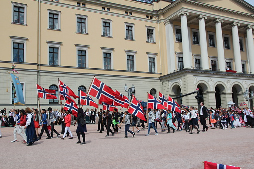 Oslo, Norway - May 17, 2016: National day parade in front of the castle. The Royal family is on the balcony waving to the people. Here a school with flags.