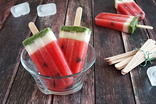 istock Watermelon popsicles in a clear bowl against a rustic wood 531780658