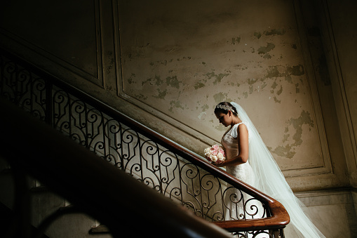 A beautiful Hispanic bride standing on his stairway in a home in Havana Cuba.