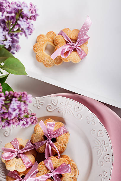 istock Biscuits with pink ribbon on white plate with lilac flowers 531783394