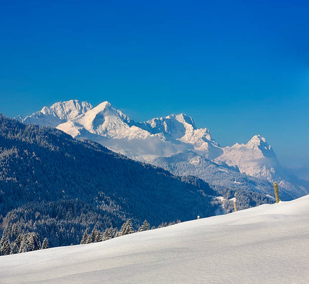 Wonderful shot of a snowy track in Garmisch-Partenkirchen on an amazing winter day. Looking like winter wonderland you can see the Waxenstein and the Zugspitze as parts of the Wetterstein, a mountain range in the Northern Limestone Alps. The Zugspitze is also Germany's highest mountain.
