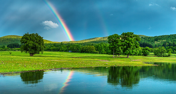 Rainbow over a lake, reflected in the water.