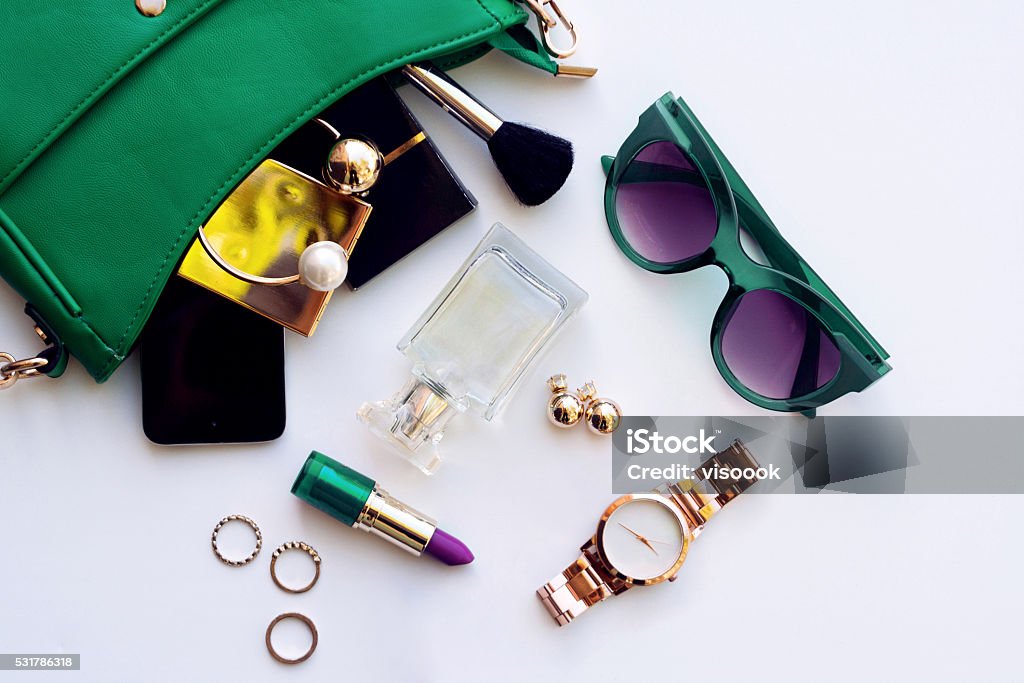 Top view of female fashion accessories Top view of female fashion accessories . Green hanbag with  sunglasses,  gold watch , lipstick , perfume , rings , smartphone Personal Accessory Stock Photo