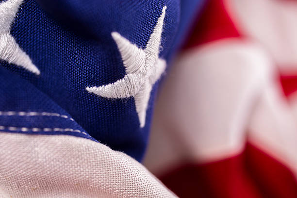 Close-up view of the red, white, and blue American flag with many folds. The stars and stripes makes a great patriotic background. No people. Flat angle. Symbolic of various holidays: Memorial Day, Veteran's Day, July 4th. Many concepts: patriotism, respect, honor, freedom, heroes, serivce, country, voting, dedication.