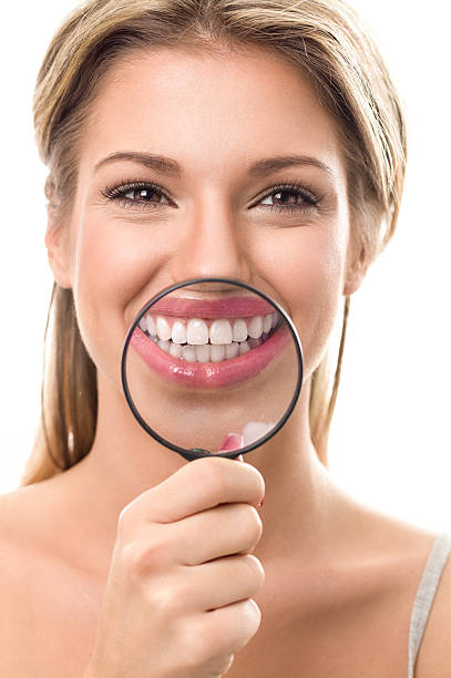 istock girl with perfect teeth behind magnifying glass 531789140