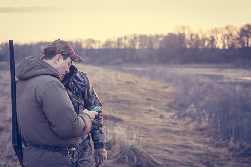 Hunters in rural field during hunting season holding smartphone and checking their location via GPS