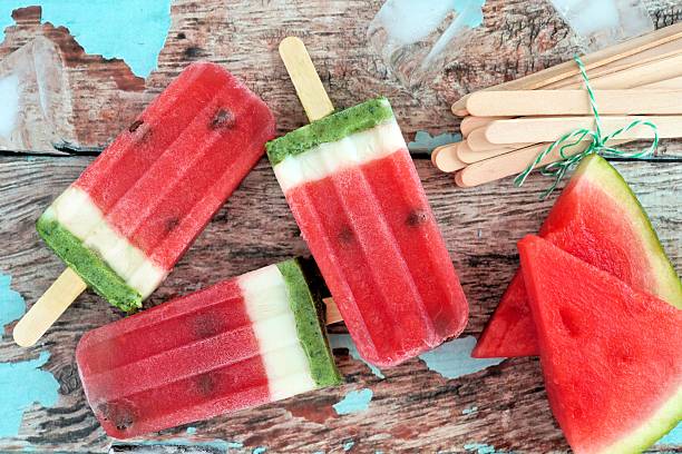 Watermelon ice pops with melon slices against rustic wood Homemade watermelon ice pops with melon slices against rustic wood background homemade icecream stock pictures, royalty-free photos & images