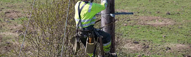 Photo of Linesman working at height harnessed on an electric power line