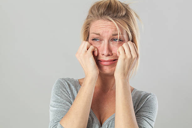 drama for blond woman crying with big tears expressing disappointment drama concept - upset young blond woman crying with big tears expressing her disappointment and sadness, grey background studio wiping tears stock pictures, royalty-free photos & images