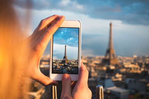 Close up of a tourist photographing Paris (Eiffel Tower) with smart phone.
