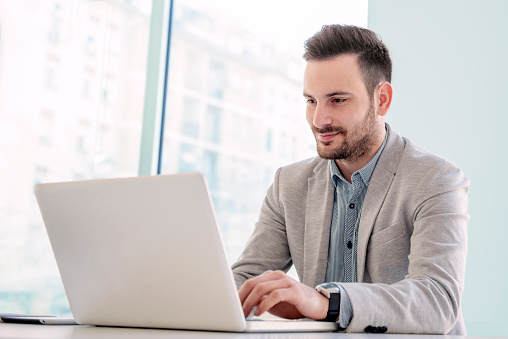 Shot of a young businessman sitting in his office.He is working on his laptop in the office.