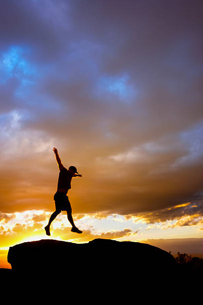 istock silhouette man jumping into sunset sky 531792515