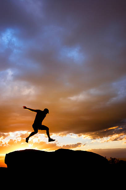istock silhouette man jumping into sunset sky 531792539