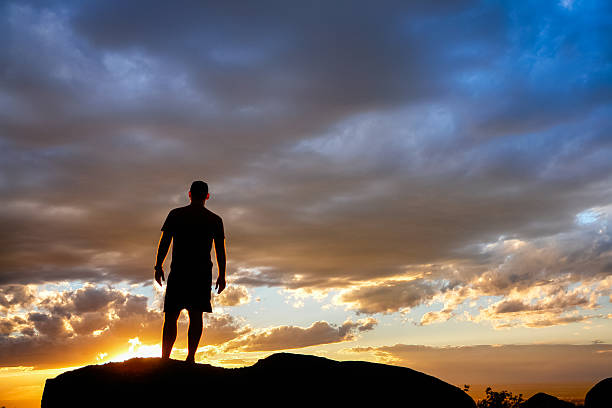 istock standing silhouette man looking at sunset sky 531792567