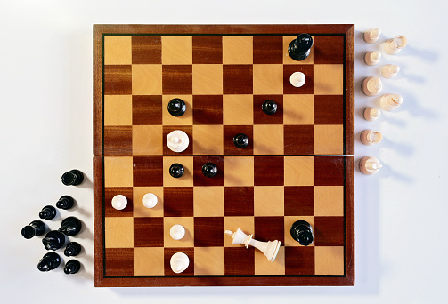 Seen from directly overhead, the end of a chess game. The white king has fallen.