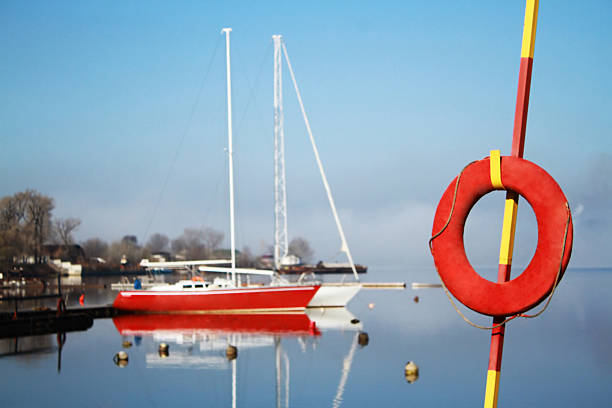 roten rettungsring auf einem hintergrund von zwei yachten - water reflection marina life jacket stock-fotos und bilder