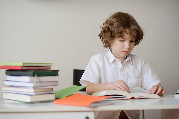 istock Schoolboy sitting at the desk and reading a book 531798754