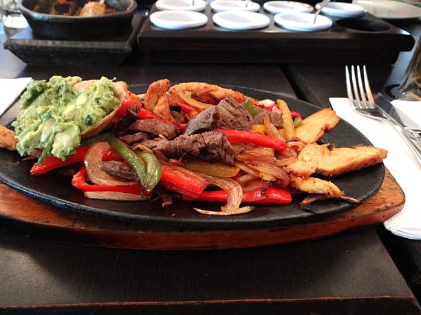 Mexican fajitas beef and chicken dish with guacamole