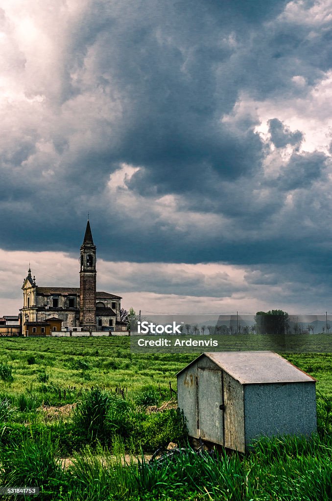 Antica chiesa nei pressi di un campo sotto cielo Pianura Padana stormy - Foto stock royalty-free di 2015