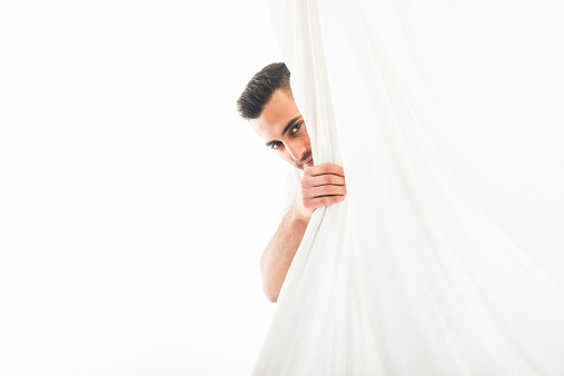 Young Man Peeping Through Curtain