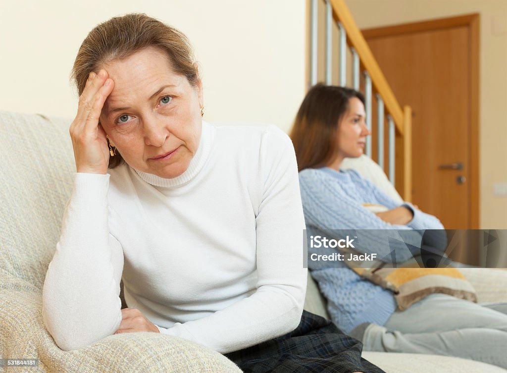 Mother and daughter after quarrel Serious  woman and teenage daughter after quarrel on sofa  in home interior 2015 Stock Photo