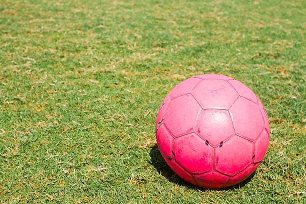 Photo of old pink soccer ball  on soccer ball green field  sunrise