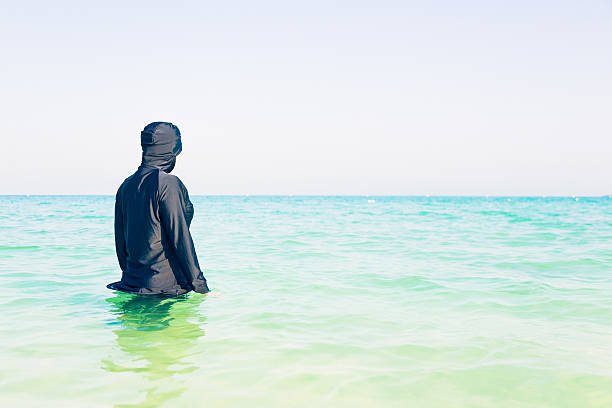 young woman in burkini swimming in the sea stock photo