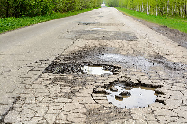 Broken road in the woods Pits of water on the asphalt road in the forest rudeness stock pictures, royalty-free photos & images