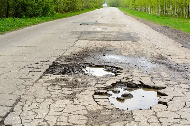 Pits of water on the asphalt road in the forest