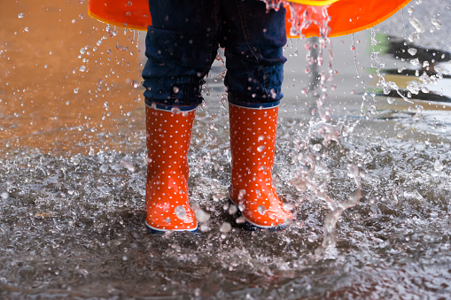 Little girl jumping into  a puddle