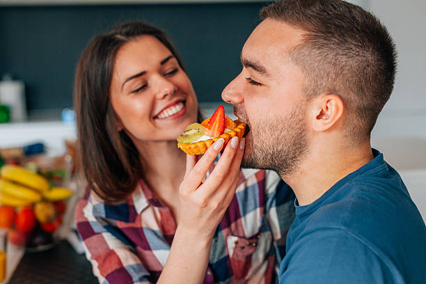 Girl feeds her boyfriend with capcakes with fruits. stock photo