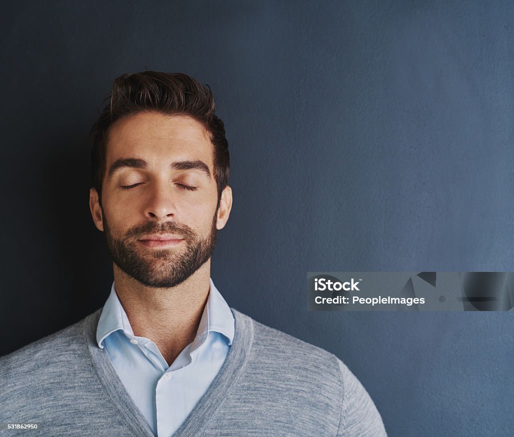 Turning my dreams into reality Shot of a handsome young businessman posing against a dark background Eyes Closed Stock Photo
