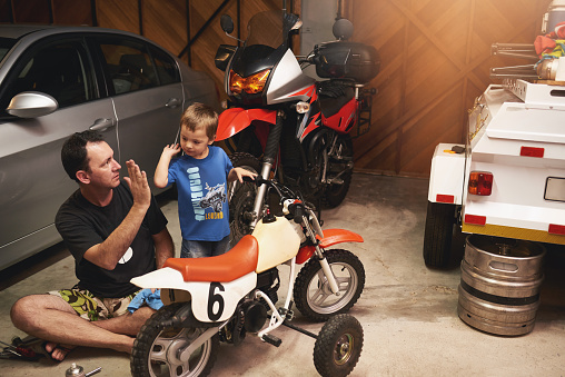 Shot of a father and son fixing a bike in a garage