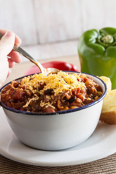 istock Bowl of Chili With Corn Bread Muffin Hand Scooping 531866385