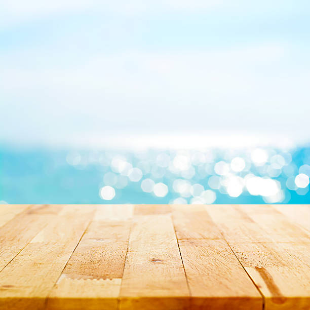 istock Wood table top on blur sparkling summer blue sea background 531866844