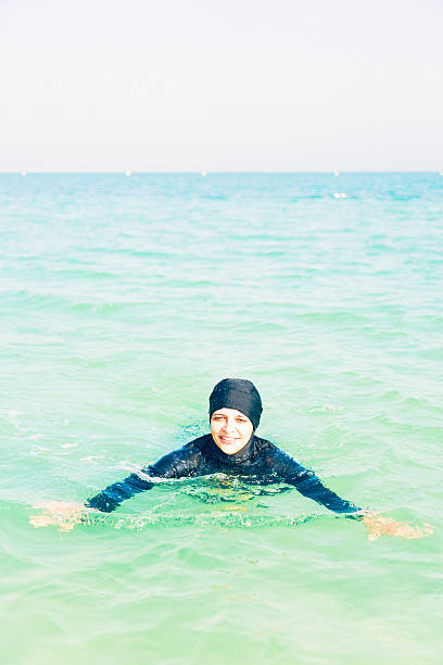 young woman in burkini swimming in the sea - 回教泳裝 圖片 個照片及圖片檔