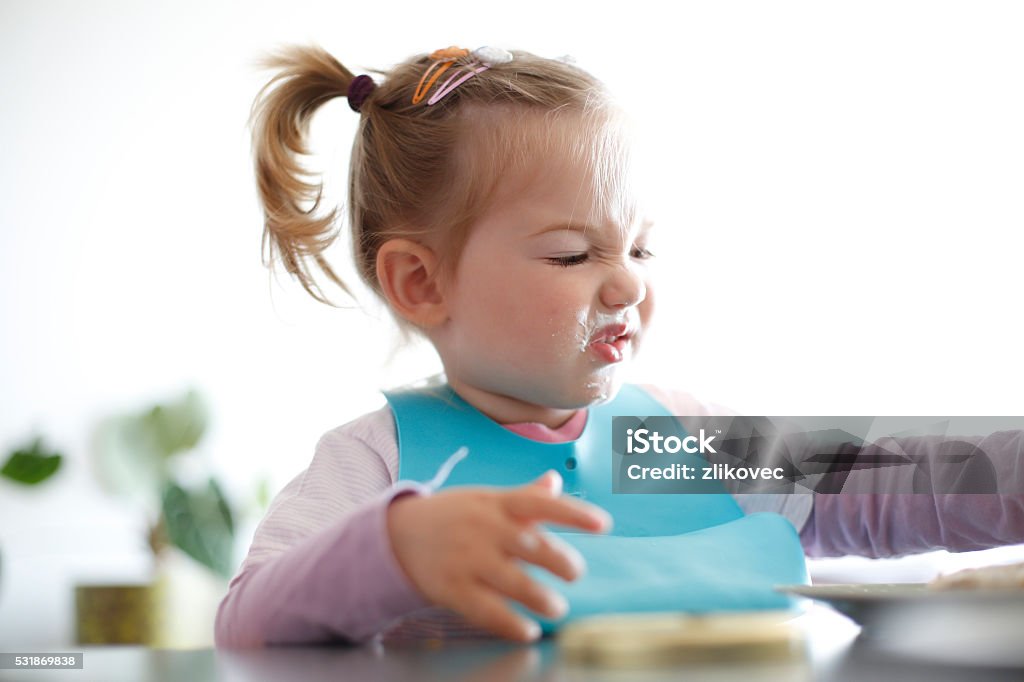 Little girl toddler picking her food, making faces Little girl toddler picking her food, making faces. Childhood problems, picky eater, eating habits, terrible two concept. Eating Stock Photo