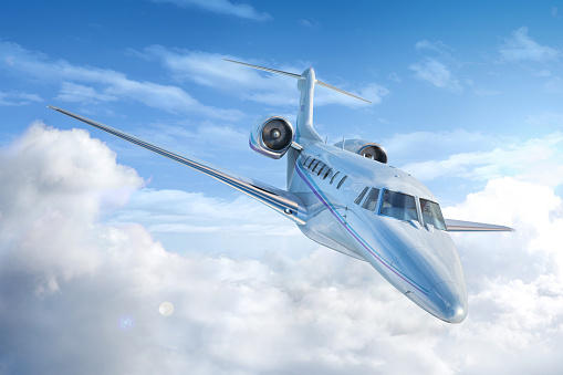Private Jet airplane flying. Perspective/front view. With sky and clouds background.
