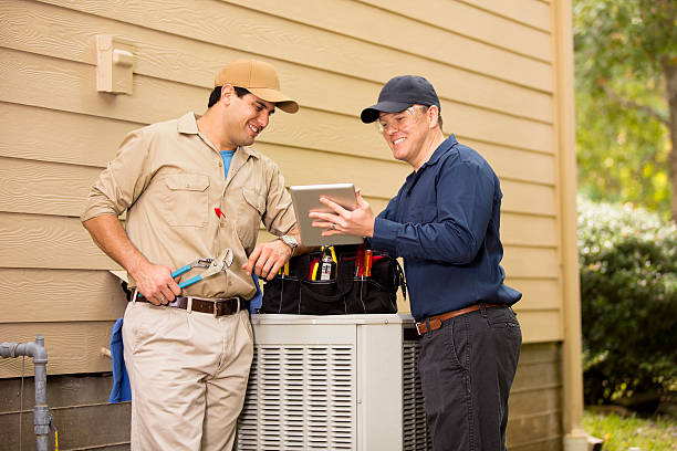 Air conditioner repairmen work on home unit. Blue collar workers. stock photo