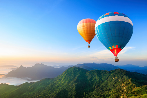 Scenic summer landscape with hot air balloon, forest and mountains.