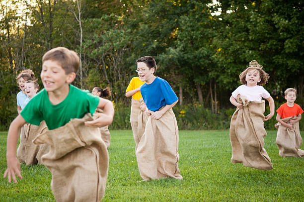 group of happy children having картофель бег в мешках за - child playing sack race sports race стоковые фото и изображения