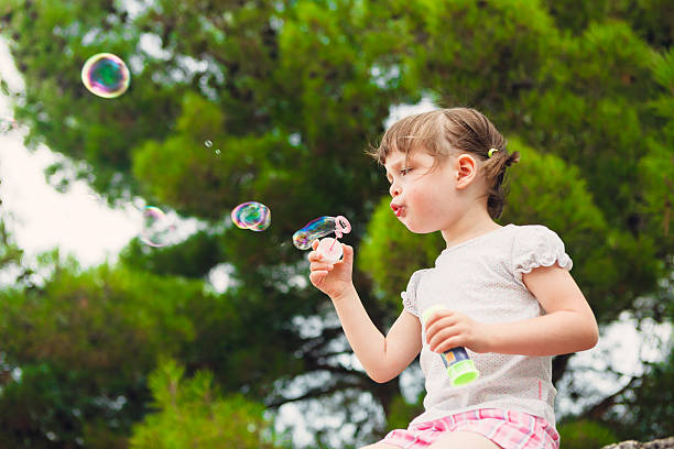 istock cute little girl blowing soap bubbles 531887135