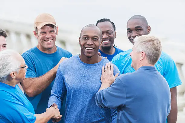 Photo of African American man being congratulated by friends