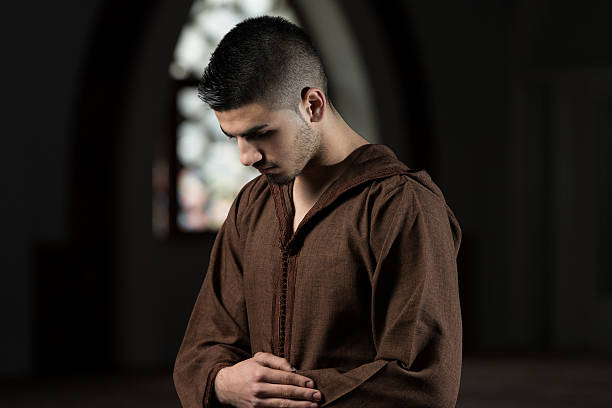 Young Muslim Man Making Traditional Prayer To God While Wearing A Traditional Cap Djellaba