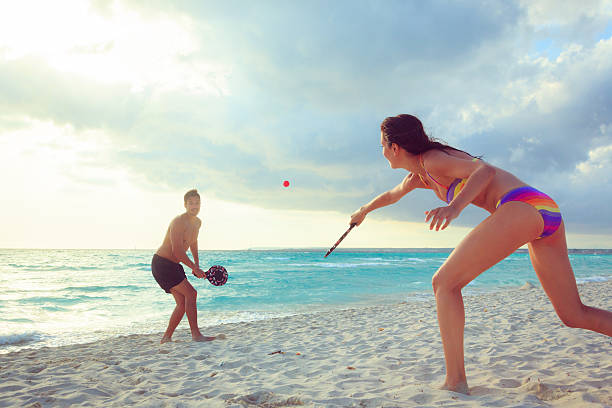 young couple playing beach tennis stock photo