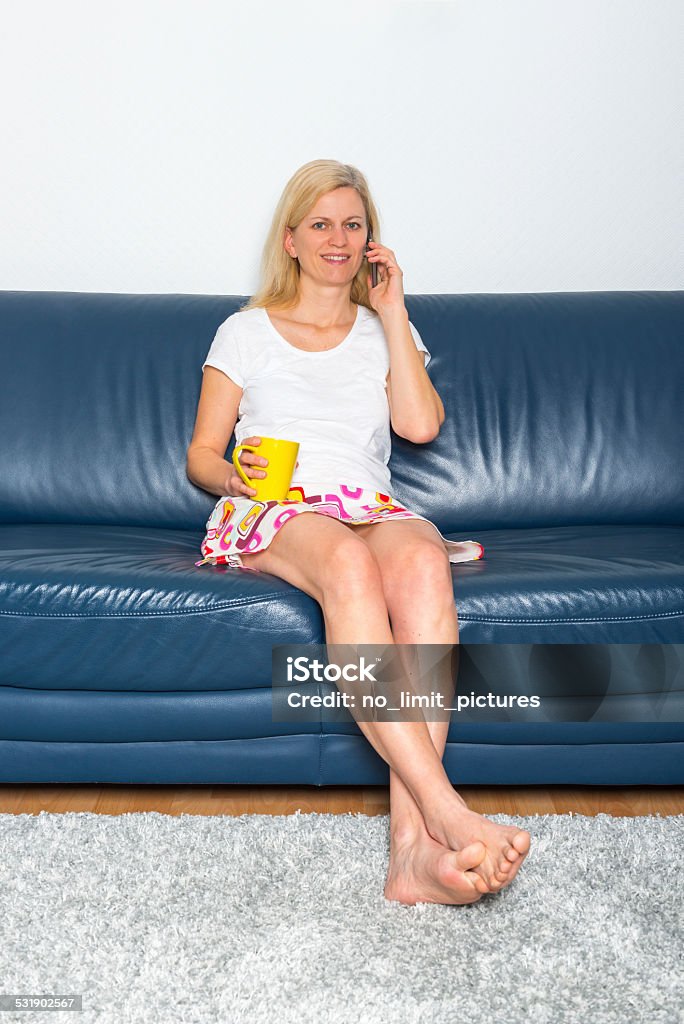 woman relaxing on a sofa woman with a mobile phone and coffee is sitting on a sofa 2015 Stock Photo