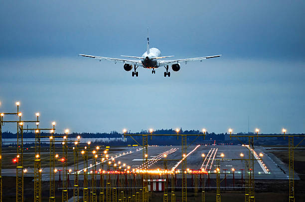 avion atterrissant au runway tard le soir - landing photos et images de collection