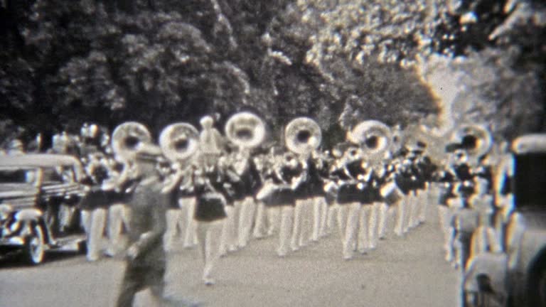 1937: Marching band parading with tuba band horns playing.