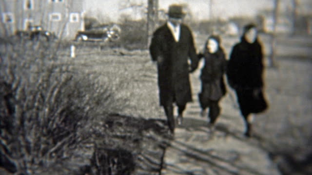 1937: Happy family skipping down the sidewalk in wealthy neighborhood.